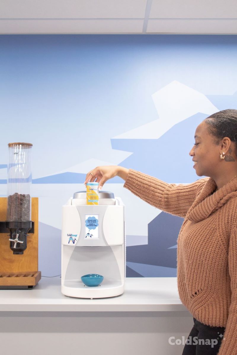 A woman inserting a pod into the Coldsnap frozen treat machine