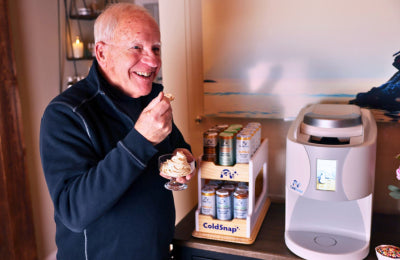Man enjoying an ice cream dessert next to a ColdSnap machine and Cold Snap product display.