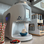 ColdSnap® frozen treat machine sitting on a kitchenette counter next to a ColdSnap® pod display rack and toppings