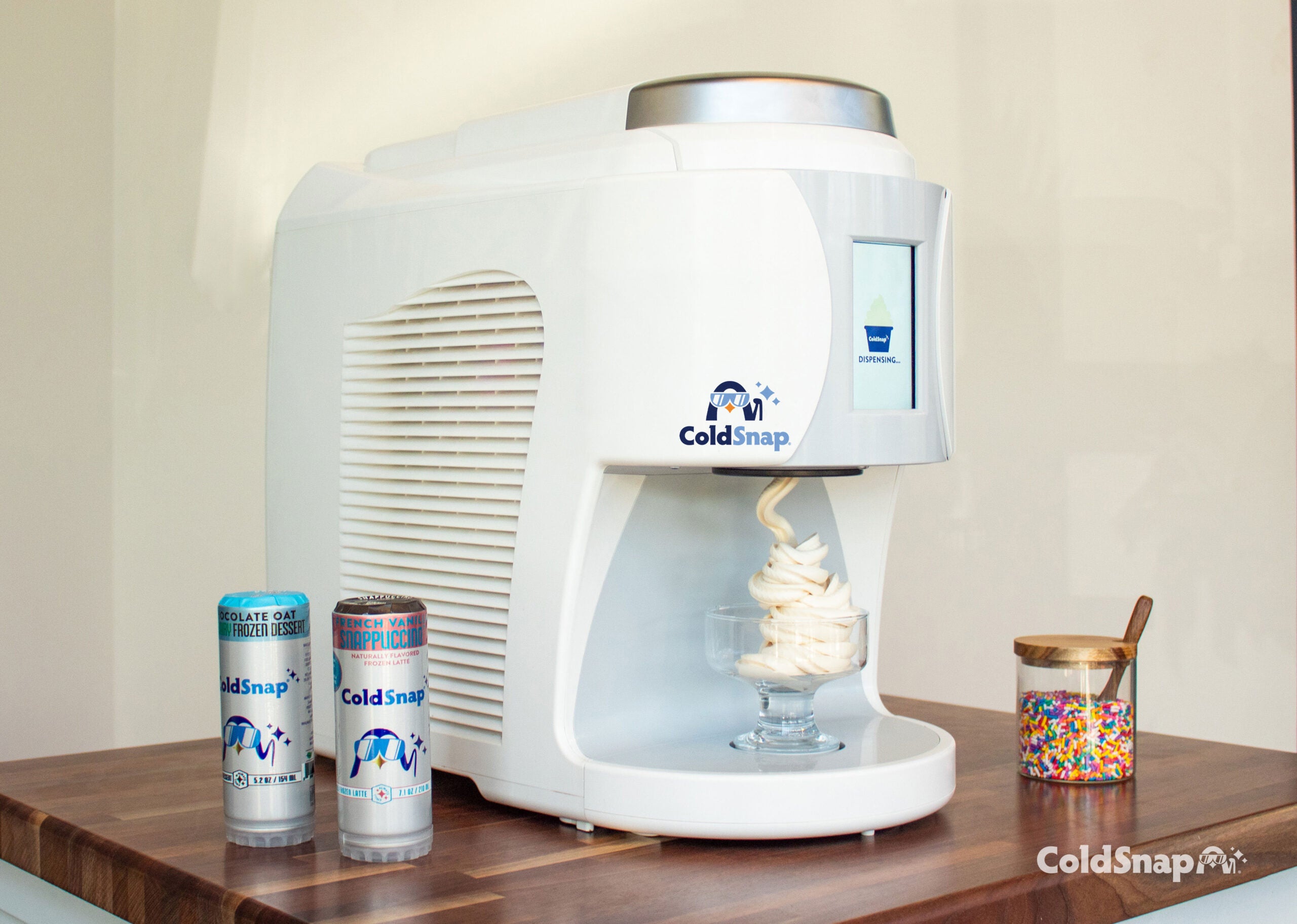 ColdSnap ice cream machine and cans on a wooden counter with a neutral background