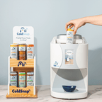 ColdSnap® pod display rack next to the ColdSnap® frozen treat machine being loaded by a user with a vanilla ice cream pod. 