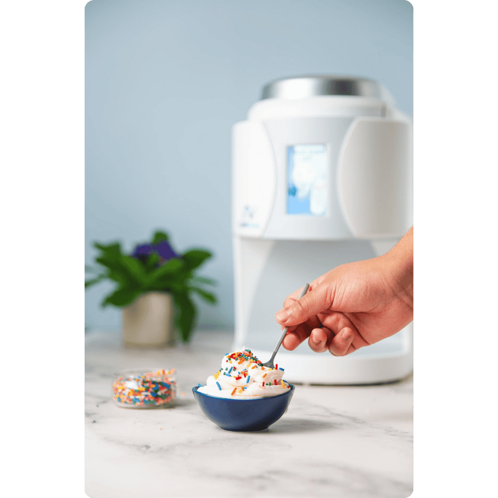 Hand scooping some ColdSnap® Vanilla Premium Ice Cream with sprinkles from a blue bowl