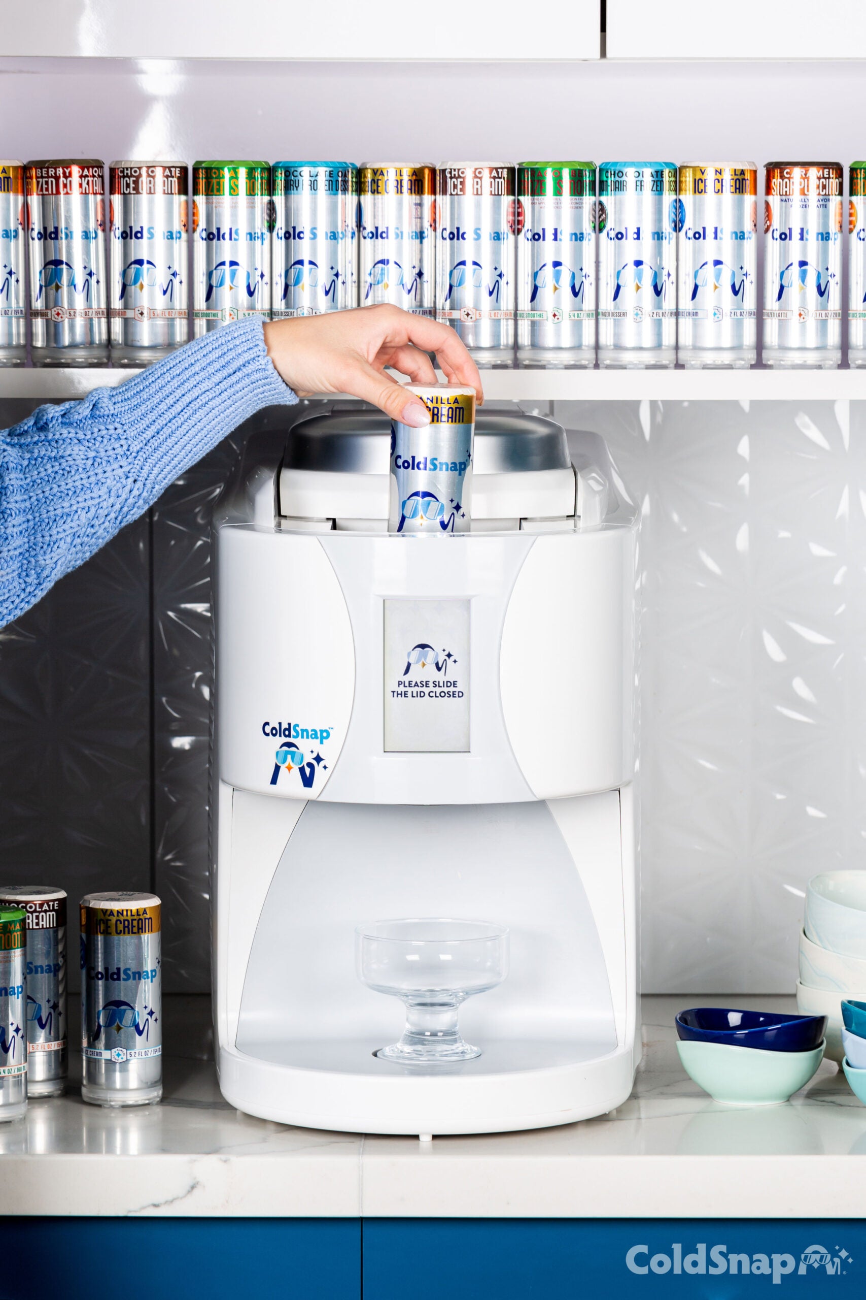 Person using a ColdSnap machine to dispense a pod of ColdSnap Premium Vanilla Ice cream in a kitchen setting.