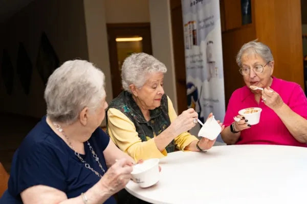Three elderly women sitting around a table, enjoying bowls of ColdSnap ice cream.